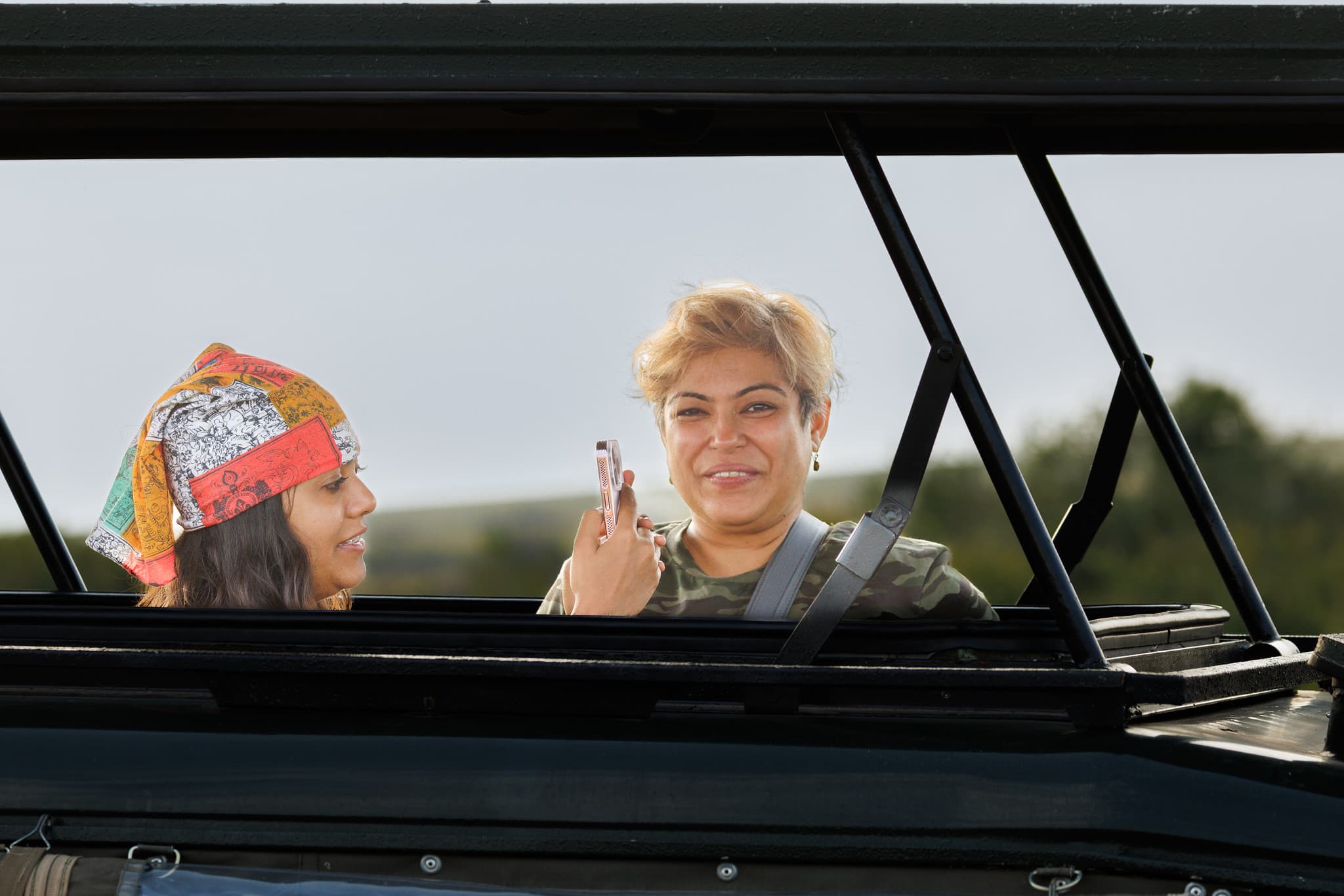 Guests shooting from the pop-top roof hatch of a safari vehicle on the Masai Mara. © Nitin Vyas