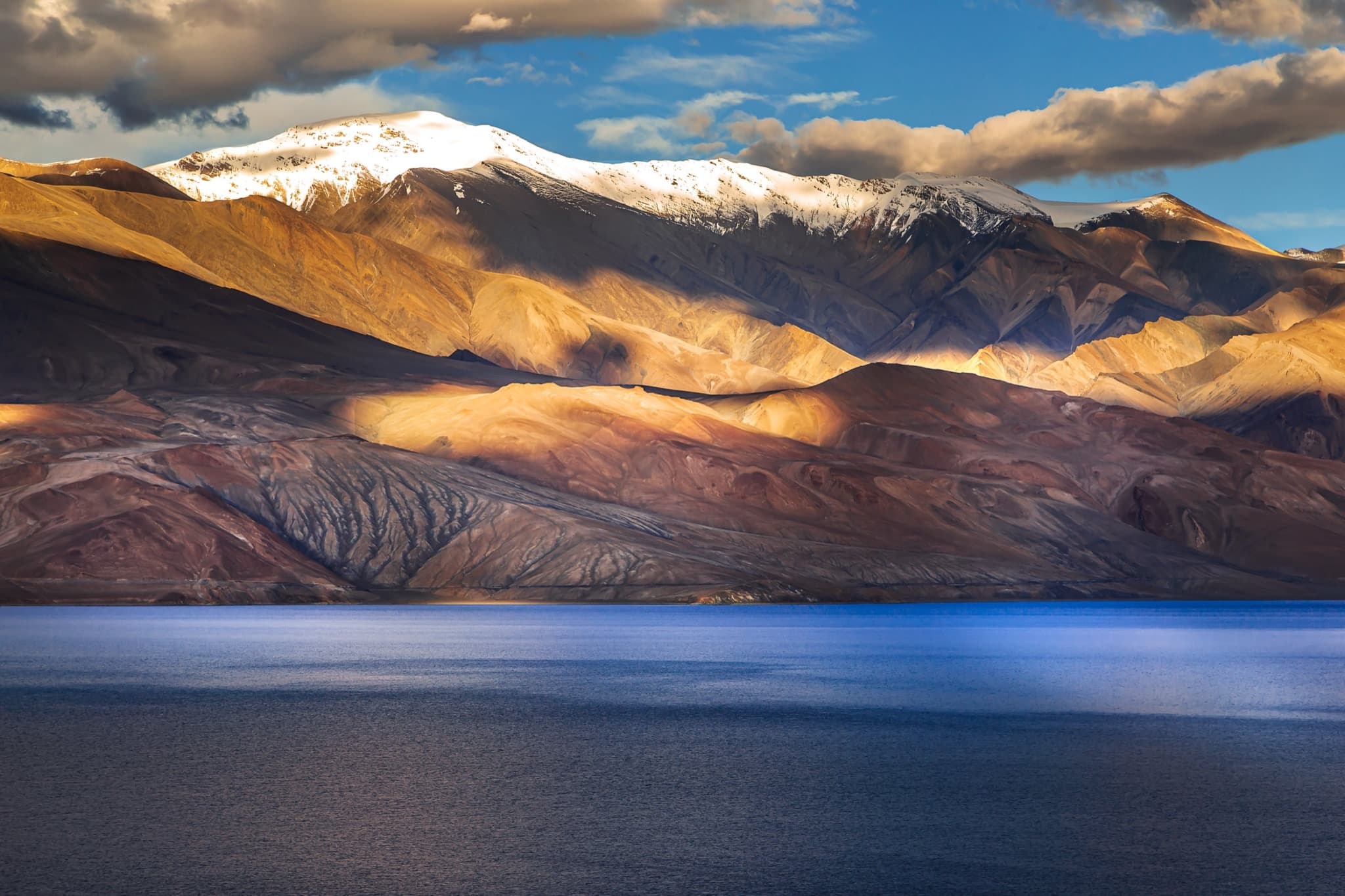 Tso Moriri lake at sunset with golden mountains and snow-capped peaks in Ladakh